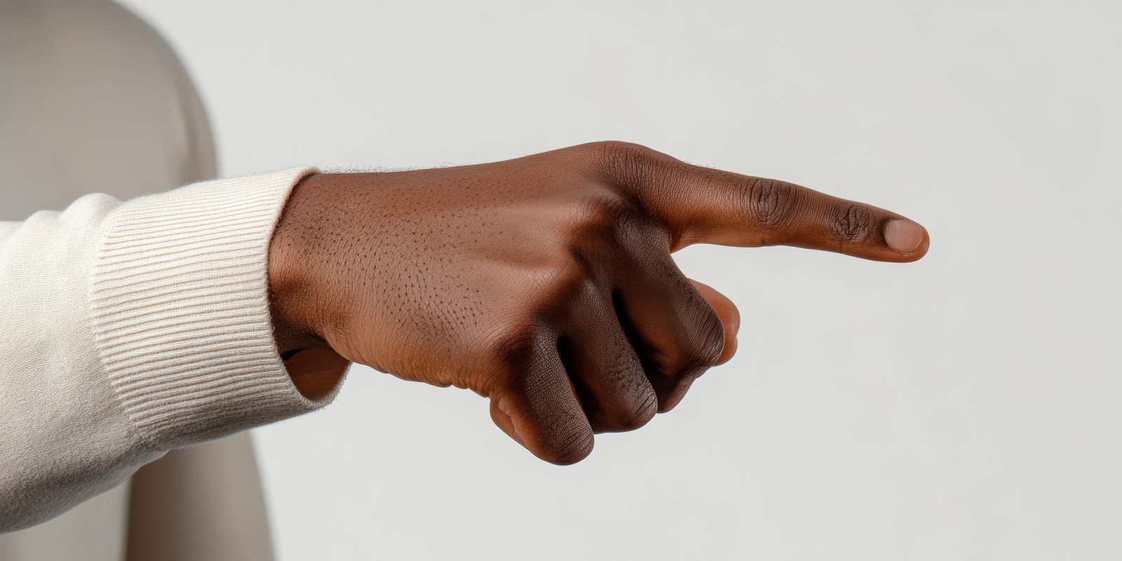 Hand gesture indicating direction displayed by a person wearing a white sweater in a neutral setting